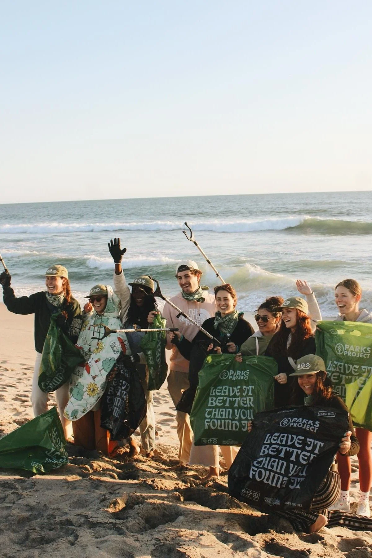Group of volunteers holding banners and cleanup tools after a beach cleanup
